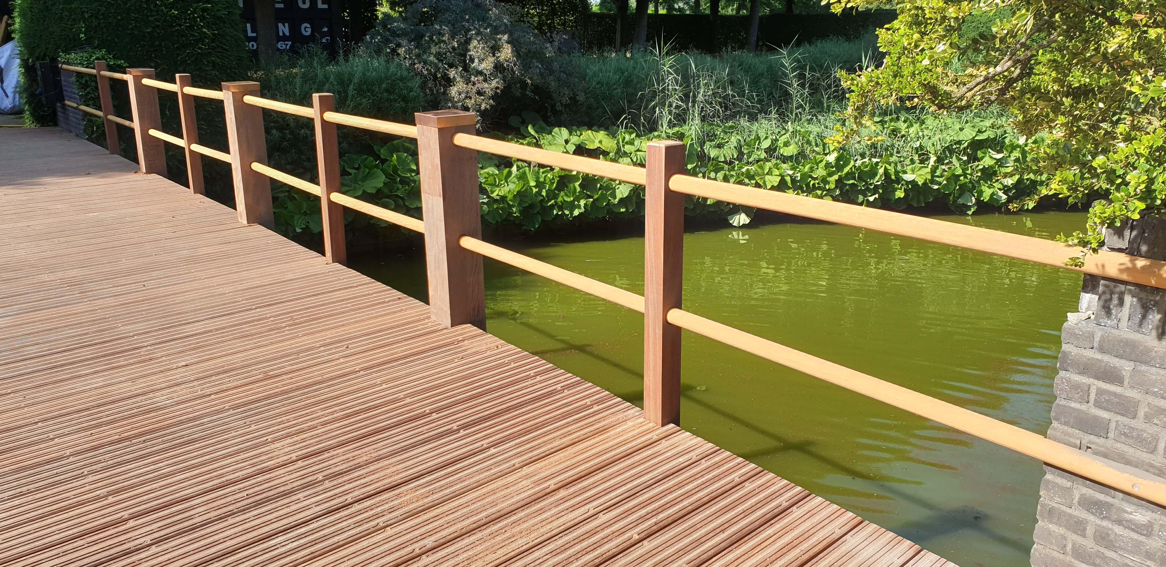 rechte houten toegangsbrug over het water tussen het groen