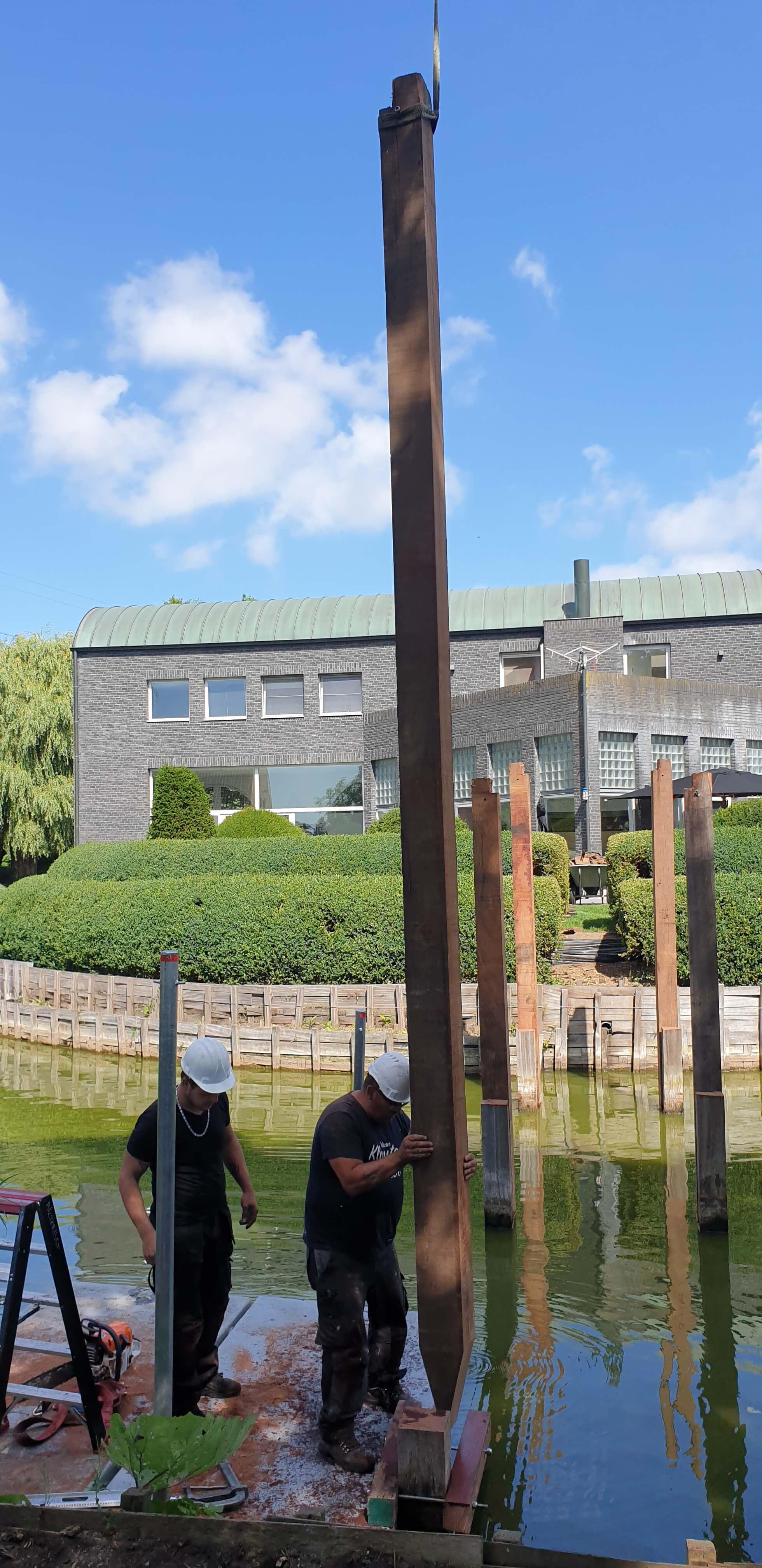 2 mensen die een houten stijger in het water steken