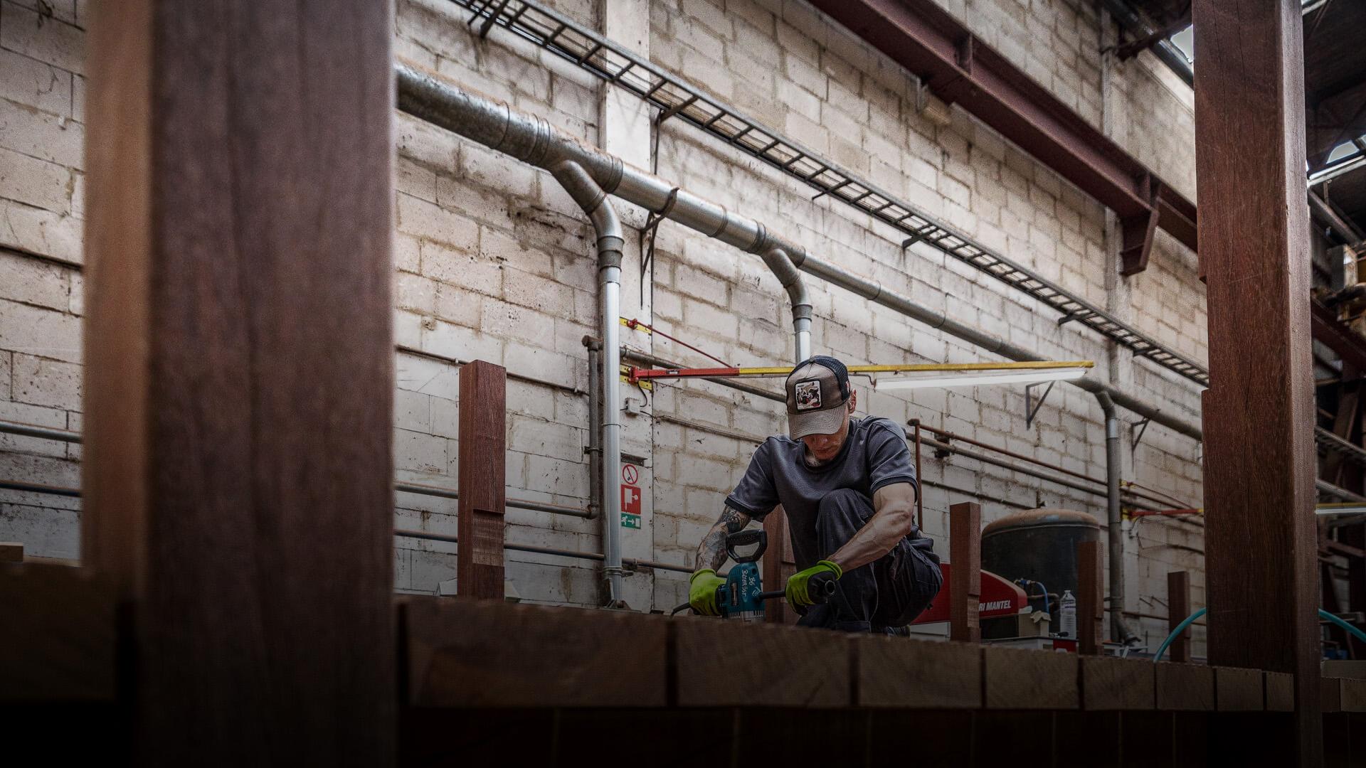 Werknemer met pet werk aan een brug in het atelier van Woodrow