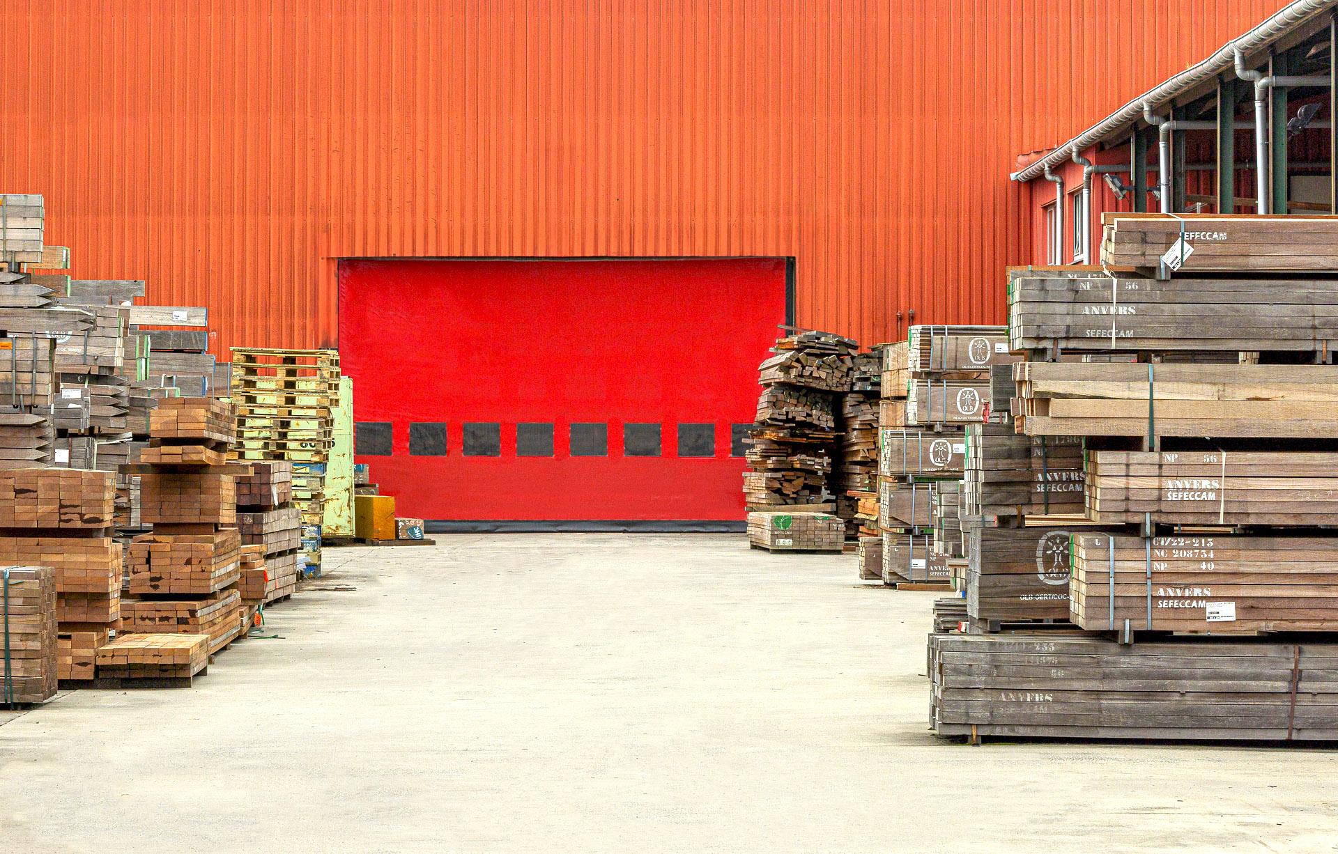 oranje gebouw met rode rolpoort, houten balken